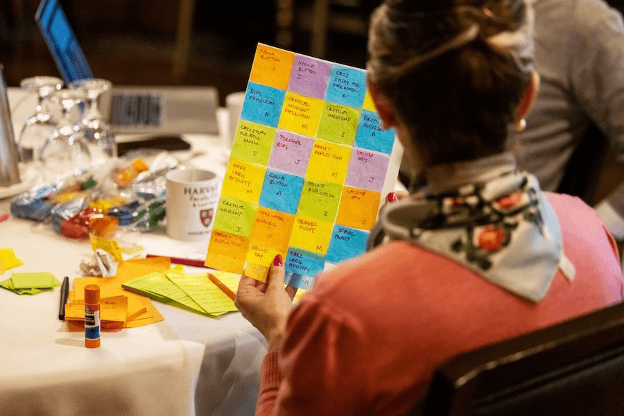 A person learning the i5 Playbook in a conference room and holding up a paper sheet with sticky notes attached.